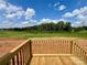 Sunny back deck has wooden rails with a view of the grassy backyard and distant trees at 188 Trivette Rd, Harmony, NC 28634