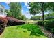 Lush backyard featuring manicured lawn, mature trees, and view of pond with fountain at 19946 River Falls Dr, Davidson, NC 28036