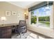Bright home office with a large window overlooking a serene pond with a fountain at 19946 River Falls Dr, Davidson, NC 28036