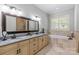 Luxurious bathroom featuring dual sinks, granite countertops, and a relaxing soaking tub with shuttered windows at 6211 Cruden Bay Way, Charlotte, NC 28277