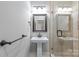 Modern bathroom featuring a pedestal sink, dark fixtures, and a tiled shower with glass door at 6211 Cruden Bay Way, Charlotte, NC 28277