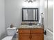 Powder room featuring a granite countertop, wood cabinets, framed mirror, and neutral wall color at 6211 Cruden Bay Way, Charlotte, NC 28277