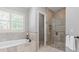 Bathroom features a soaking tub, glass enclosed shower, and neutral tile throughout at 6211 Cruden Bay Way, Charlotte, NC 28277