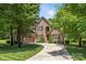 Elegant brick home featuring a spacious three-car garage and lush, green landscaping, with manicured lawn at 6211 Cruden Bay Way, Charlotte, NC 28277