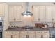 Close-up of the kitchen's gas cooktop and stainless steel vent hood, surrounded by cream-colored cabinets at 6211 Cruden Bay Way, Charlotte, NC 28277