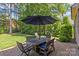 Outdoor patio with brick flooring, shady umbrella, and dark wooden table set for outdoor dining at 6211 Cruden Bay Way, Charlotte, NC 28277