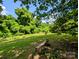 View of backyard and garden with mature trees and stone bench at 647 Mckay Hill Rd, Mount Gilead, NC 27306