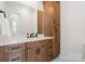Bathroom featuring wood cabinets, granite countertops, black hardware, and a large mirror at 722 Clegg Farm Dr, York, SC 29745