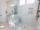 Modern bathroom showcasing glass shower with bench and built-in shelves against neutral wall and floor tiles at Lot 29 Bozeman Ct # 29, Stanley, NC 28164