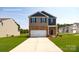 Two-story home boasts a manicured lawn, brick accents, and a two-car garage, embodying suburban charm at 1044 Horizon Ln, Chester, SC 29706