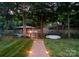 Lush backyard view through trees down a stone path to a lake and boathouse at 116 Creeky Hollow Dr, Mooresville, NC 28117