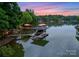 Picturesque waterfront view featuring a private boat dock, lake access, and lush surrounding trees at sunset at 116 Creeky Hollow Dr, Mooresville, NC 28117