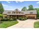 Charming two-story home with a well-manicured lawn, mature trees, and a welcoming front porch at 116 Creeky Hollow Dr, Mooresville, NC 28117