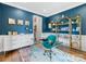 Home office with blue walls, a glass desk, gold shelving, and colorful decor at 15313 Moate Ct, Huntersville, NC 28078
