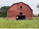 Exterior of a weathered red barn surrounded by tall grass, a classic farm feature at 18070 Old Beatty Ford Rd, Gold Hill, NC 28071