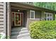 A covered front entrance with a red door and stone accents is surrounded by lush greenery at 2045 10Th Street Nw Ln, Hickory, NC 28601
