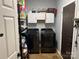 Functional laundry room equipped with modern black washer and dryer, storage cabinets, and ample space at 208 Stone Ridge Dr, Salisbury, NC 28146
