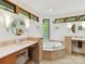 Serene bathroom with a soaking tub, dual vanities, natural stone accents and multiple windows at 218 Point Carpenter Rd, Fort Mill, SC 29707