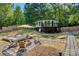 A backyard featuring a fire pit, deck, a home with a porch, and wooded scenery at 295 Rendleman Rd, Salisbury, NC 28146