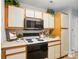 Kitchen featuring white cabinets, black appliances, and warm wood accents at 317 Cedarcroft Dr, Mooresville, NC 28115