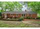 Exterior view of a brick home with a patio, chairs, and well-maintained landscaping at 6749 Windyrush Rd, Charlotte, NC 28226