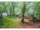 Backyard featuring mature trees, green lawn, garden shed, and a brick patio at 6749 Windyrush Rd, Charlotte, NC 28226