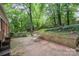 Brick patio, garden bed, and mature trees creating a serene backyard setting at 6749 Windyrush Rd, Charlotte, NC 28226