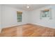 Spacious bedroom featuring hardwood floors, neutral walls, ceiling fan, and natural light from the windows at 6749 Windyrush Rd, Charlotte, NC 28226