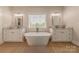 Bright bathroom with a soaking tub situated between two vanities with marble countertops and white cabinets at 1134 Fincher Rd, Fort Lawn, SC 29714