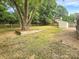 Spacious backyard with a large tree, wooden planter, shed, and a wooden fence at 1212 Beechdale Dr, Charlotte, NC 28212