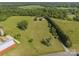 Aerial view showing vast property with farmhouse, barn, and silo surrounded by trees and grassy fields at 130 Johnson Dairy Rd, Rockwell, NC 28138