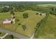Aerial view of property features a farmhouse with a large lawn, barn, silo, and surrounding green fields and trees at 130 Johnson Dairy Rd, Rockwell, NC 28138
