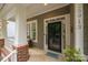 Inviting covered front porch with brick accents and charming entry door at 15913 Trenton Place Rd, Huntersville, NC 28078
