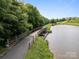 View of a serene community walking trail with a wood and steel bridge spanning a small inlet on the lake at 15913 Trenton Place Rd, Huntersville, NC 28078