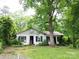 Exterior view of a quaint home surrounded by mature trees, partially enclosed by a white picket fence, needs renovation at 206 Rose Ter, Wadesboro, NC 28170