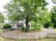 View of a large home featuring a circular driveway and a charming picket fence, surrounded by mature trees at 206 Rose Ter, Wadesboro, NC 28170
