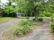 Charming exterior shot with lush landscaping, a detached garage, and a circular driveway bordered by a white picket fence at 206 Rose Ter, Wadesboro, NC 28170