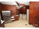 Rustic kitchen with wood paneled walls, stainless steel refrigerator, and laundry area at 206 Rose Ter, Wadesboro, NC 28170