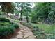 Lush backyard featuring a stone pathway surrounded by vibrant flowers and greenery at 211 Southfork Dr, Belmont, NC 28012