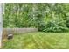 Spacious, grassy backyard with an air conditioning unit and wood fence bordering lush, mature trees at 2333 Wednesbury Ct, Kannapolis, NC 28083
