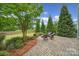 Beautiful backyard with a stone patio featuring a fire pit and chairs, surrounded by trees and shrubs at 295 Helton Ln, Fort Mill, SC 29708