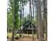 Modern farmhouse with dark siding nestled in trees, featuring a garage and natural wood porch columns at 3020 Quiet Ln, Iron Station, NC 28080