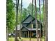 Two-story modern farmhouse with dark siding, a garage, and natural wood accents nestled in a wooded lot at 3020 Quiet Ln, Iron Station, NC 28080