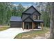Modern farmhouse with dark siding, garage, natural wood porch columns, and a concrete driveway at 3020 Quiet Ln, Iron Station, NC 28080