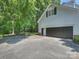 Spacious garage with black garage door and extended driveway surrounded by green trees and landscape at 5308 Sunningdale Dr, Charlotte, NC 28277