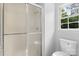 Bright bathroom featuring a shower stall with glass doors, a toilet, and a window at 6412 Sullins Rd, Charlotte, NC 28214