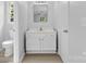 Bathroom features a white vanity and mirror, a toilet, and wood-look vinyl floors at 6412 Sullins Rd, Charlotte, NC 28214