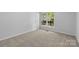 A bright bedroom featuring neutral carpeting and a window offering a view of the outdoors at 6412 Sullins Rd, Charlotte, NC 28214