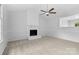 Inviting living room featuring a brick fireplace, ceiling fan, and ample natural light for a cozy atmosphere at 6412 Sullins Rd, Charlotte, NC 28214