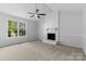 Bright living room featuring a brick fireplace, large window, and soft carpeting for a comfortable space at 6412 Sullins Rd, Charlotte, NC 28214
